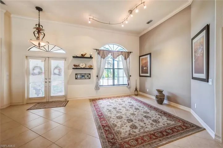 Tiled foyer entrance featuring track lighting, french doors, and crown molding