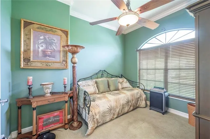 Carpeted bedroom featuring ceiling fan and crown molding