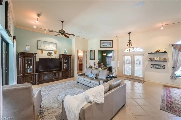 Tiled living room with crown molding, french doors, track lighting, and ceiling fan