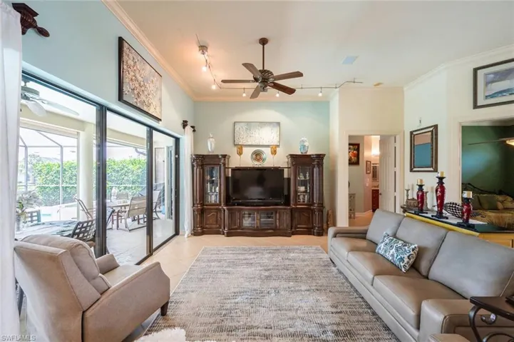 Tiled living room featuring track lighting, ornamental molding, and ceiling fan