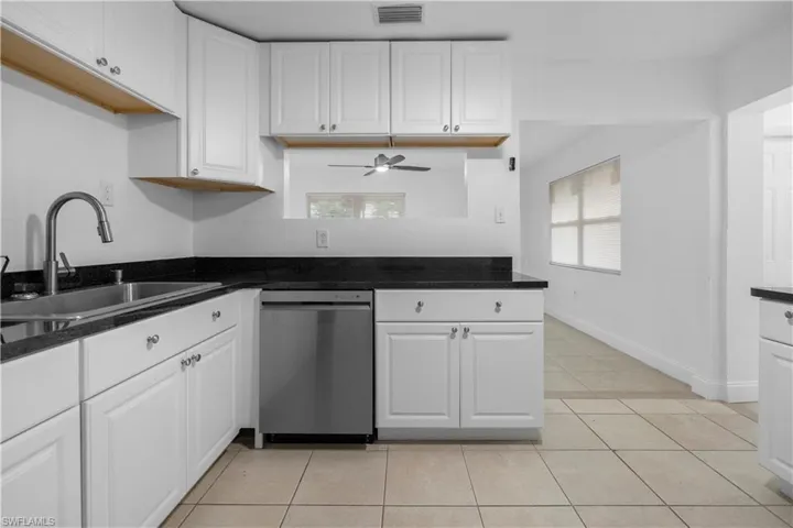 Kitchen featuring white cabinets, light tile patterned floors, dishwasher, and healthy amount of natural light