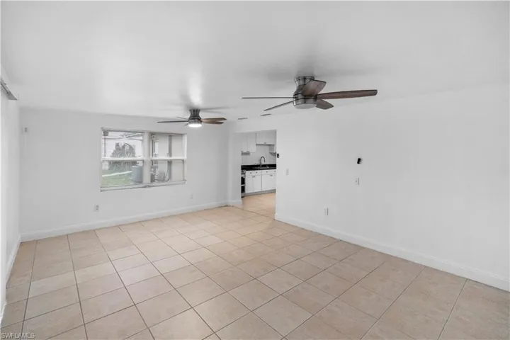 Empty room with light tile patterned floors and a ceiling fan