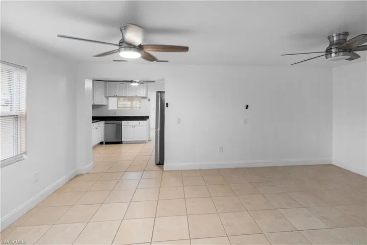 Kitchen featuring ceiling fan, dark countertops, light tile patterned flooring, stainless steel appliances, and white cabinets