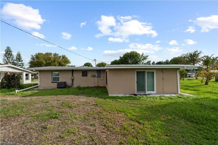 Back of house with a yard and stucco siding