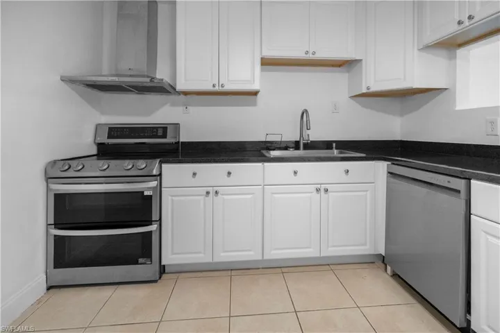 Kitchen featuring stainless steel appliances, exhaust hood, white cabinets, and light tile patterned floors