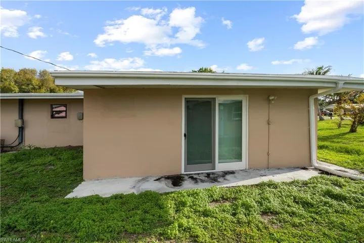 Rear view of property with a lawn and stucco siding