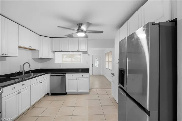 Kitchen featuring stainless steel appliances, white cabinets, a ceiling fan, and light tile patterned flooring