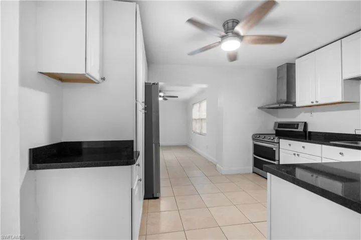 Kitchen featuring white cabinetry, range with two ovens, ceiling fan, freestanding refrigerator, and light tile patterned floors