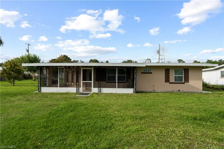 Front of property with a sunroom, a lawn, and stucco siding