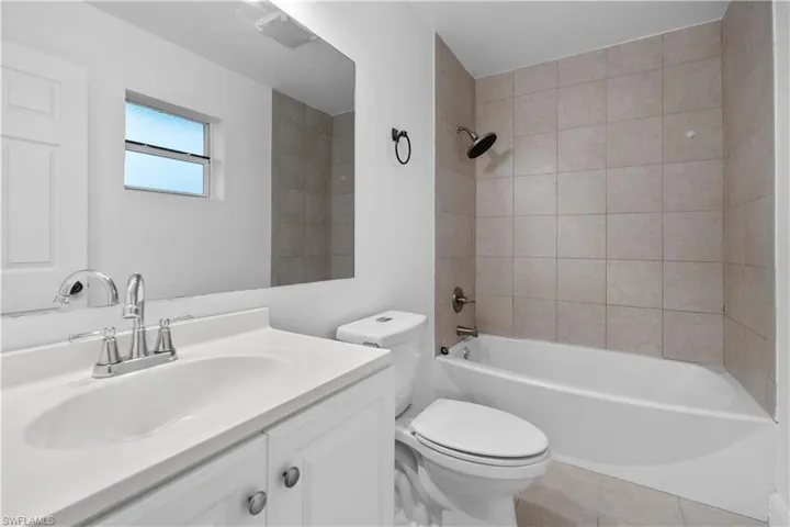 Bathroom with vanity, bathtub / shower combination, and light tile patterned floors