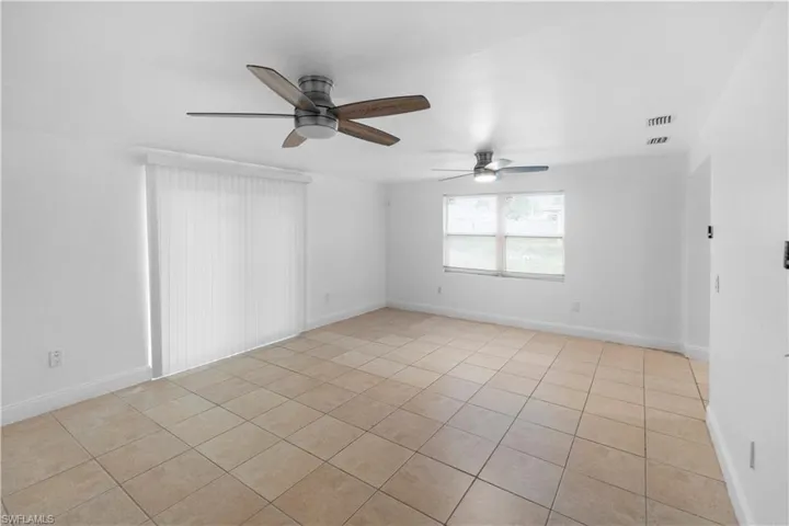 Empty room with light tile patterned floors and a ceiling fan