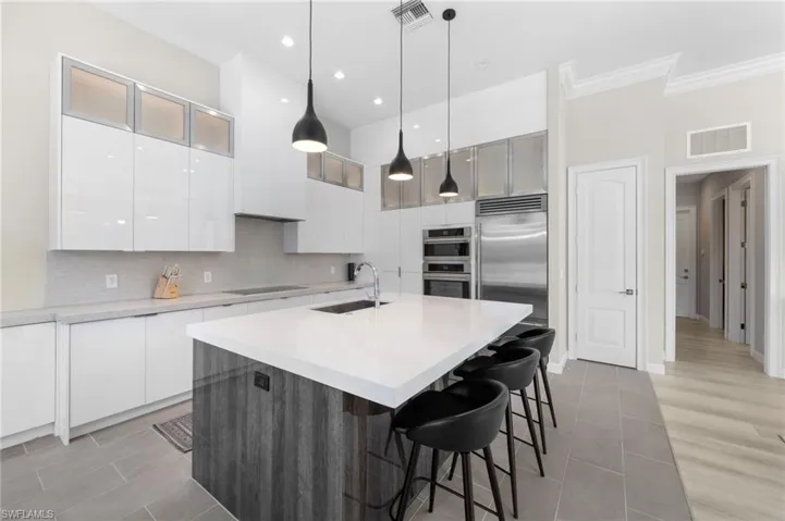 Kitchen with light hardwood / wood-style flooring, an island with sink, stainless steel appliances, backsplash, and sink