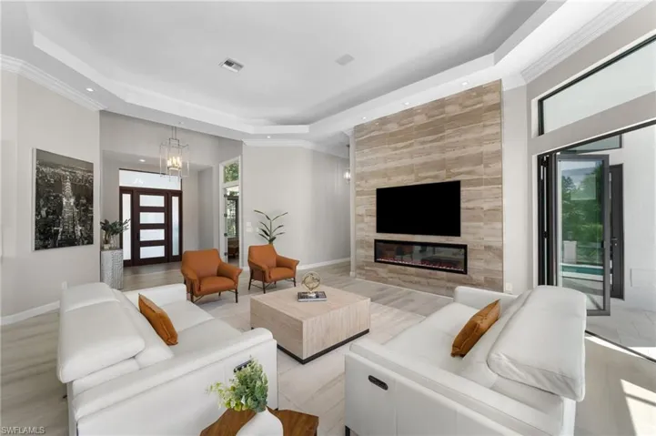 Living room with a tray ceiling, a tile fireplace, and light wood-type flooring