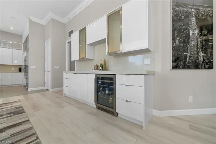 Kitchen with wine cooler, tasteful backsplash, and white cabinetry