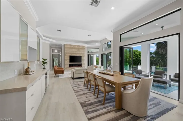 Dining space with crown molding, a raised ceiling, light hardwood / wood-style flooring, and a large fireplace