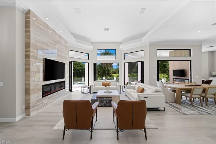 Living room featuring a healthy amount of sunlight, a large fireplace, and tile walls
