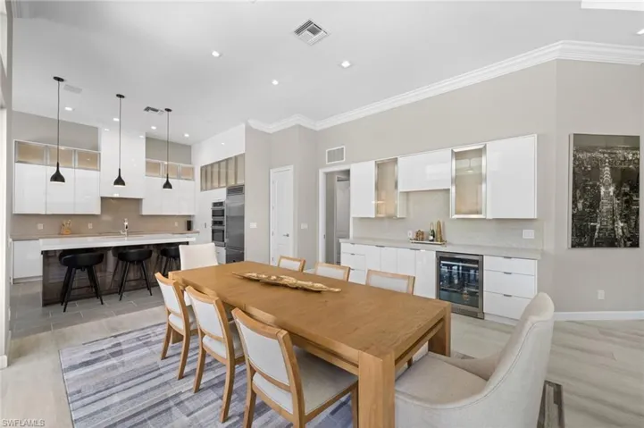 Dining area with sink, ornamental molding, light hardwood / wood-style floors, and beverage cooler
