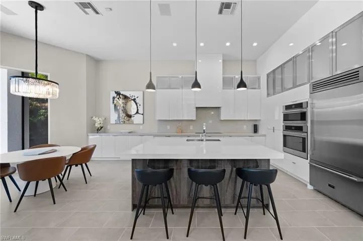 Kitchen featuring white cabinets, appliances with stainless steel finishes, and pendant lighting