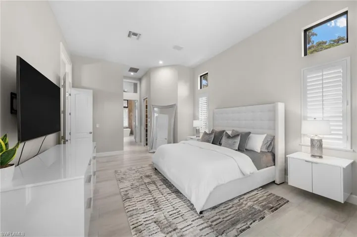 Bedroom featuring a towering ceiling and light hardwood / wood-style floors