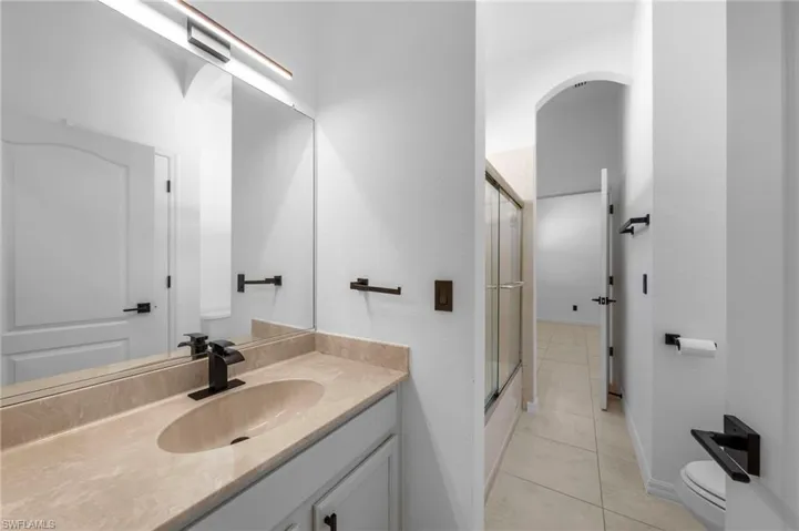 Vanity with an integrated oval sink, beige countertop, and matte black faucet