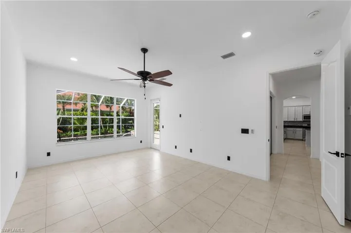 Recessed ceiling lighting, a ceiling fan with wood-finish blades, and large floor tiles