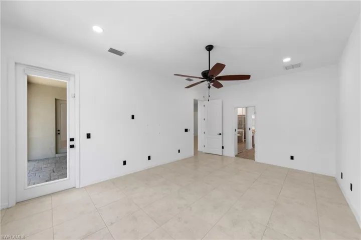 Tile flooring, recessed lighting, ceiling fan with wood-finish blades, white walls, and interior doors with black hardware