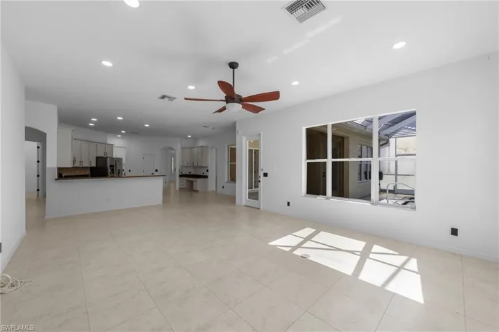 Spacious open-concept living area featuring large format tile flooring, recessed lighting, and a ceiling fan