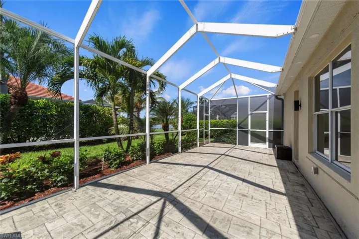Screened lanai featuring stamped concrete flooring, exterior wall sconce, and abundant natural light
