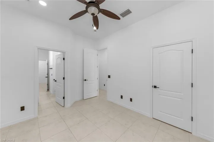 Vaulted ceiling with a ceiling fan, recessed lighting, white interior doors with black hardware, and large format tile flooring