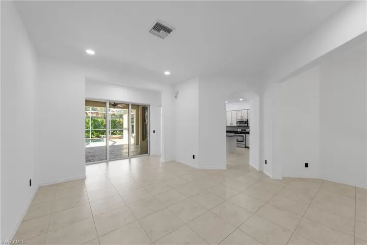 Recessed lighting, tile flooring, arched doorway, sliding glass doors, and crown molding