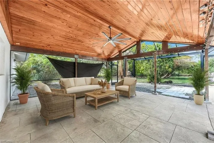 Expansive covered patio featuring a vaulted wood-plank ceiling, large ceiling fan, and patterned concrete flooring