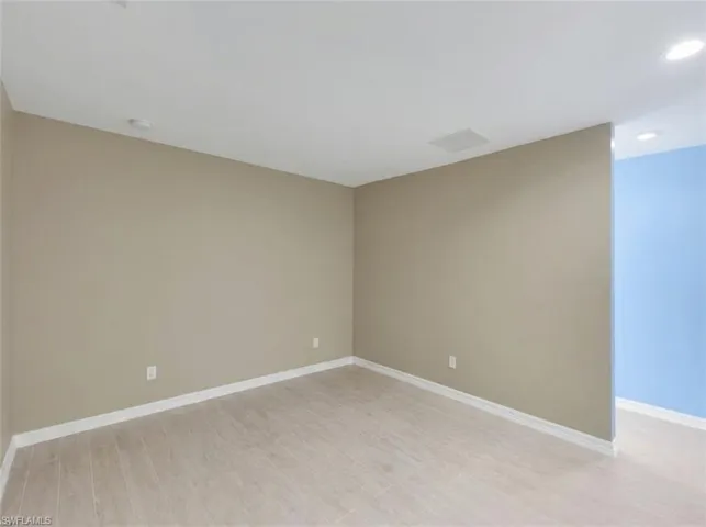 Neutral tone walls with white trim, wood-finish flooring, and recessed lighting