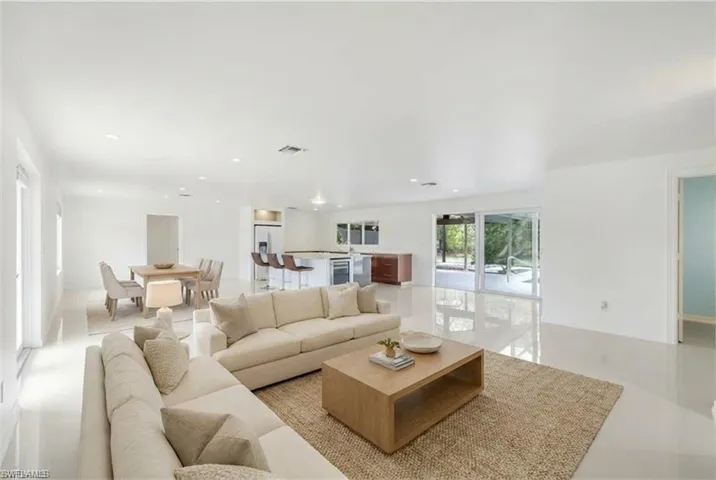 Open-concept living space featuring high-gloss tile flooring, recessed lighting, and expansive sliding glass doors