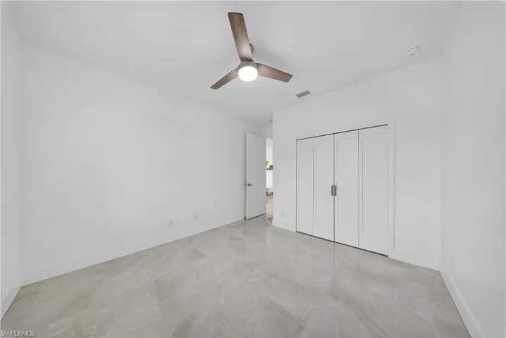 Unfurnished bedroom featuring a ceiling fan, a closet, and light marble finish floors