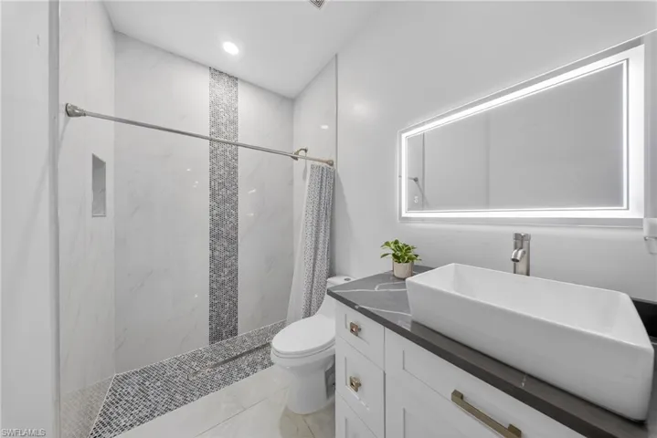 Bathroom with vanity, a marble finish shower, and recessed lighting