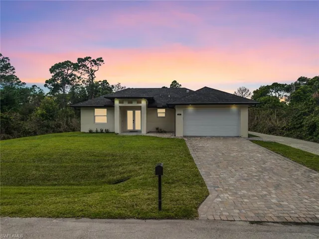 Prairie-style home with a garage, decorative driveway, stucco siding, and a yard