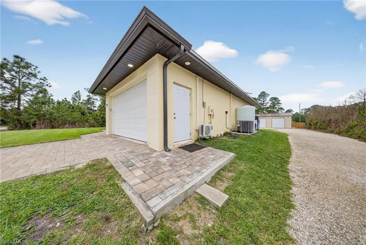 View of side of home featuring an outdoor structure, stucco siding, and a lawn