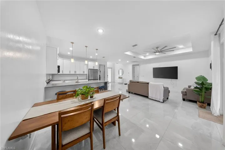 Dining area with a ceiling fan, a raised ceiling, and recessed lighting