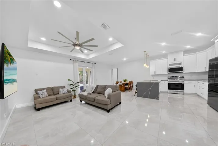 Living room featuring ceiling fan, recessed lighting, and a raised ceiling