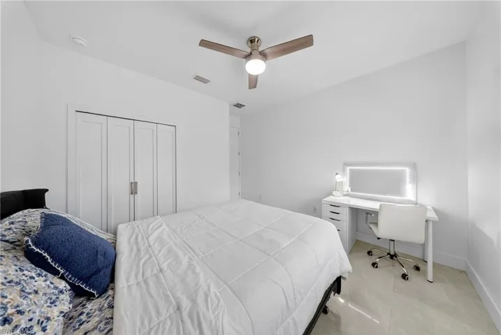 Bedroom with a ceiling fan, a desk, and a closet
