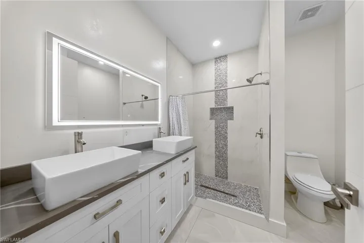 Bathroom featuring a marble finish shower and double vanity