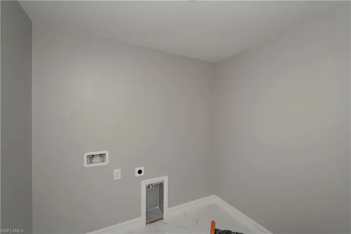 Washroom with washer hookup, hookup for an electric dryer, and marble look tiles