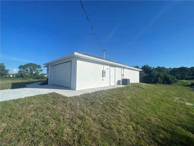 View of home's exterior featuring stucco siding, a lawn, and an attached garage