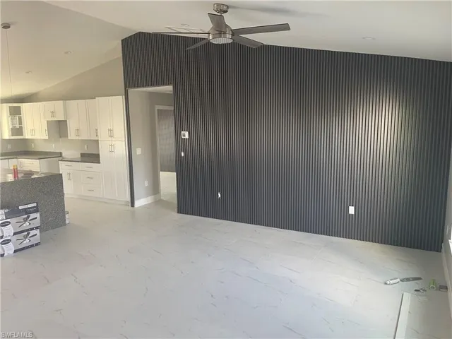 Unfurnished living room featuring vaulted ceiling and a ceiling fan