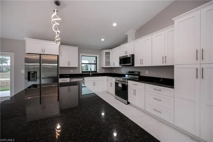 Kitchen featuring lofted ceiling, stainless steel appliances, white cabinets, recessed lighting, and pendant lighting