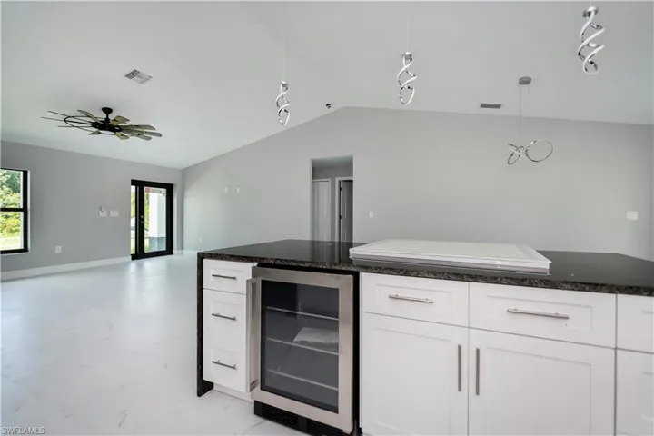 Kitchen with rail lighting, beverage cooler, open floor plan, lofted ceiling, and white cabinets