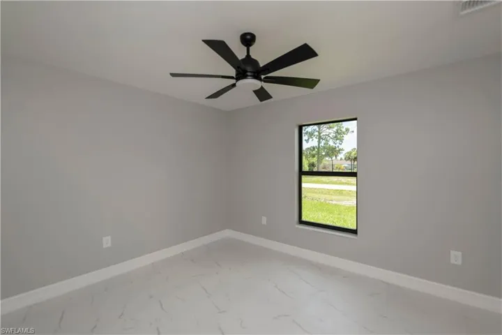 Unfurnished room featuring light marble finish flooring and a ceiling fan