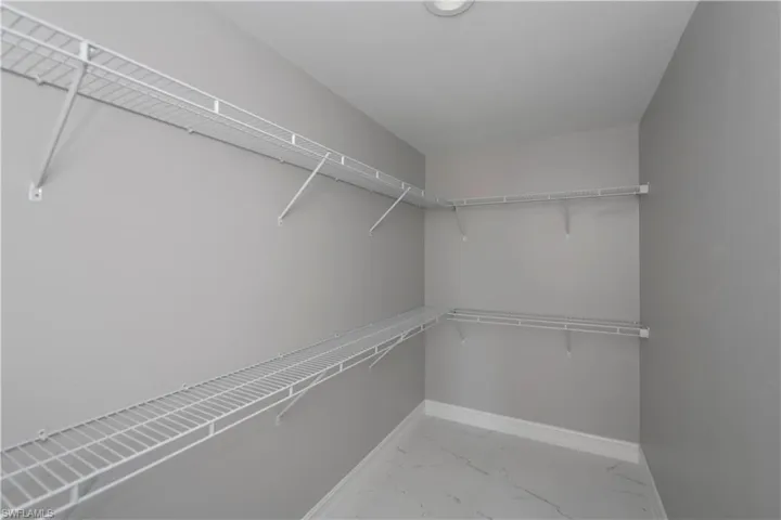 Walk in closet featuring light marble finish floors