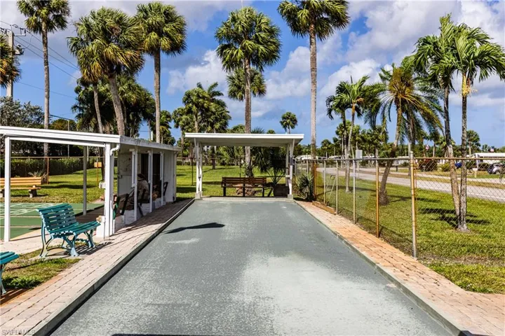 Surrounding community featuring a yard, shuffleboard, and fence