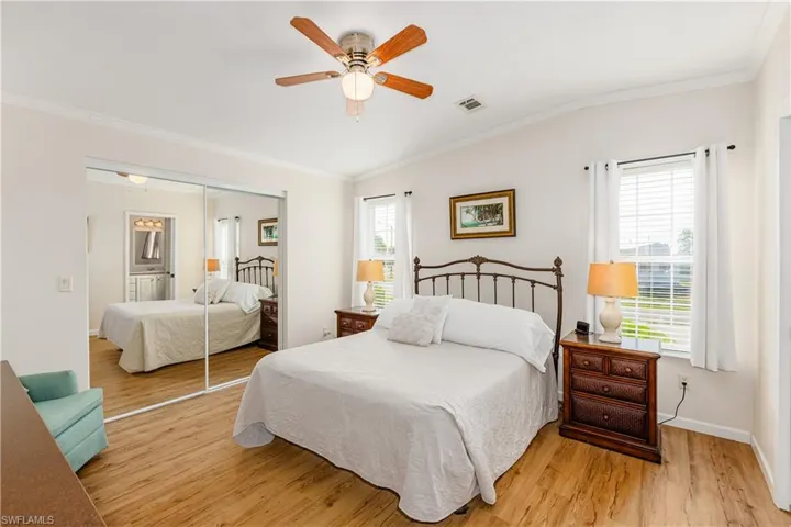 Bedroom with crown molding, visible vents, light wood-type flooring, and a closet